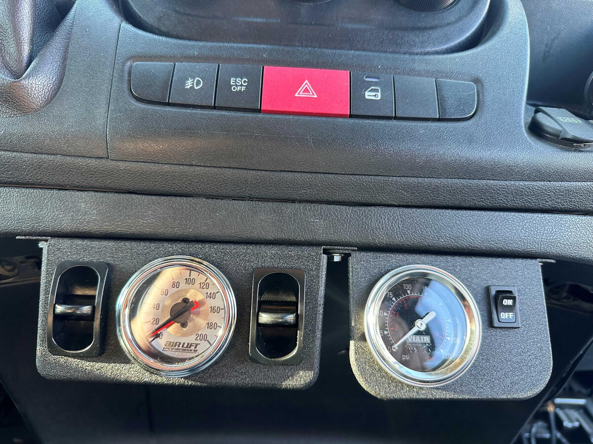 Custom in-cab air suspension controls and dual pressure gauges installed in a Ram ProMaster 3500 camper van with a VIAIR onboard air system.