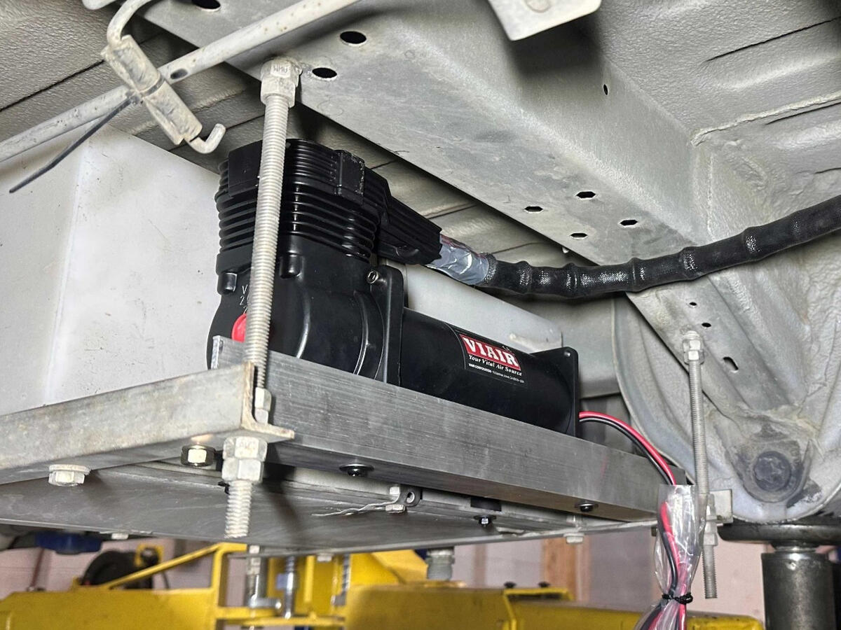VIAIR continuous-duty onboard air compressor mounted beneath a Ram ProMaster 3500 camper van as part of a custom air suspension control system.